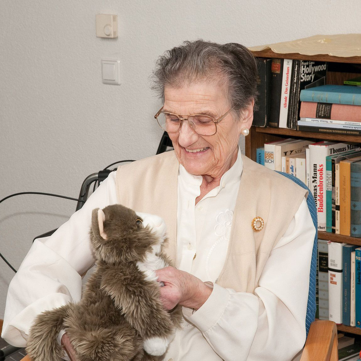 Senior lady stroking the Joyk empathy doll Billy in a living room