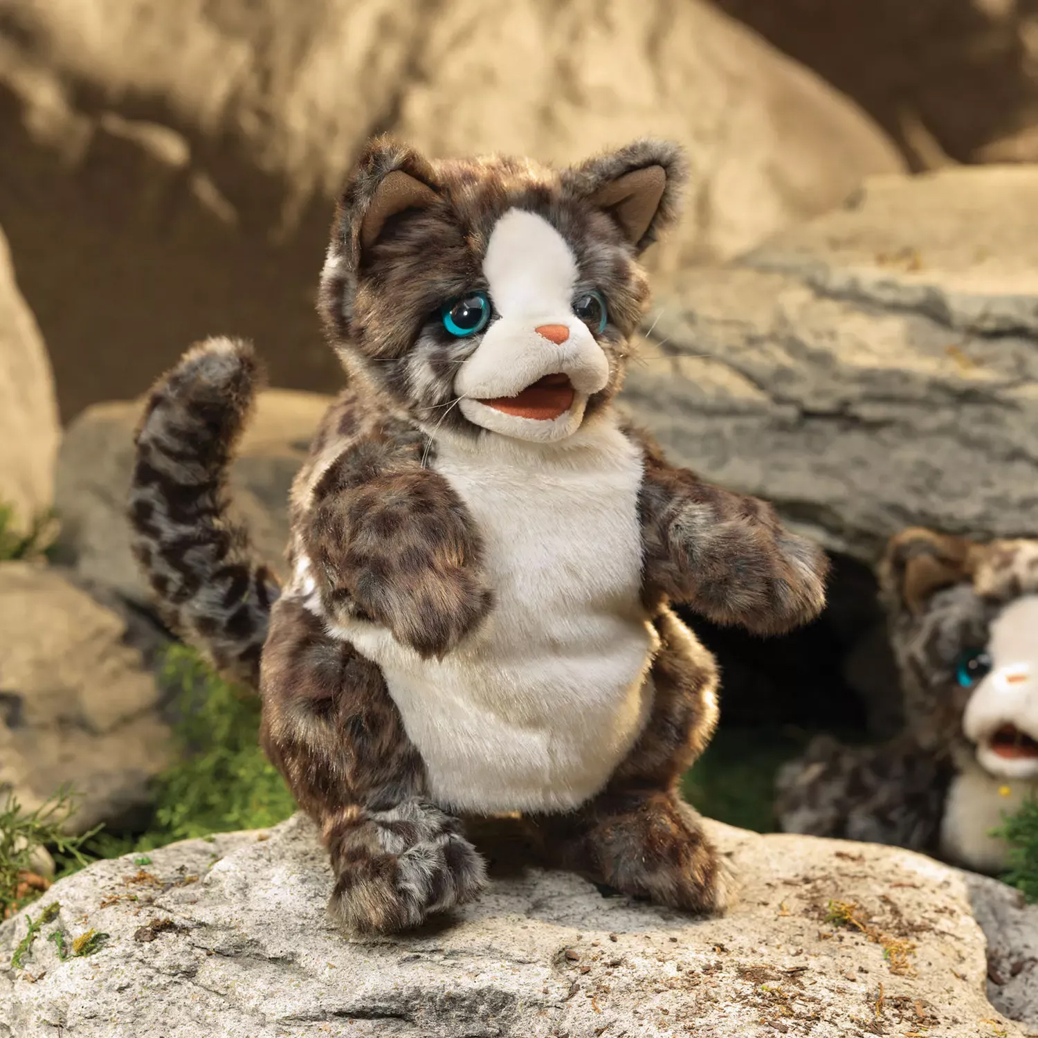 Folkmanis hand puppet wildcat kitten with brown spotted fur, white belly and turquoise eyes, standing on a rock