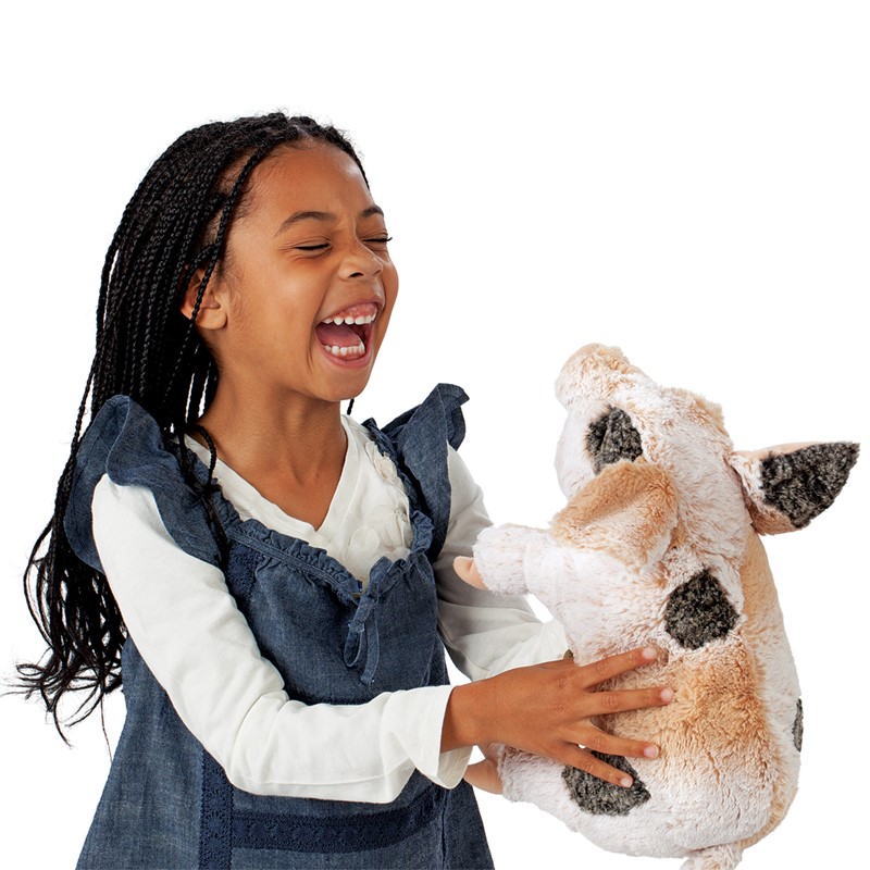 Laughing girl holding the Folkmanis grunting pig hand puppet with beige fur and dark spots in her hands