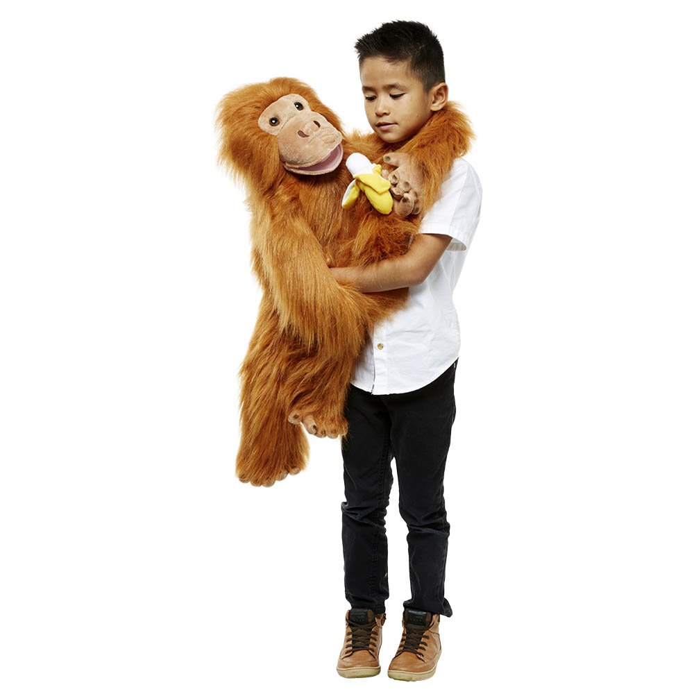 Boy holding the The Puppet Company giant orangutan hand puppet with a banana in his arms, usage example