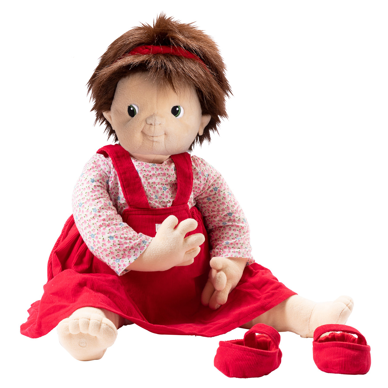 Joyk empathy doll Ingrid with a red hairband, floral shirt, red pinafore dress and little shoes, sitting