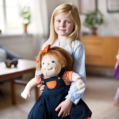 Child holding the Rubens Barn Original doll Anna in the living room