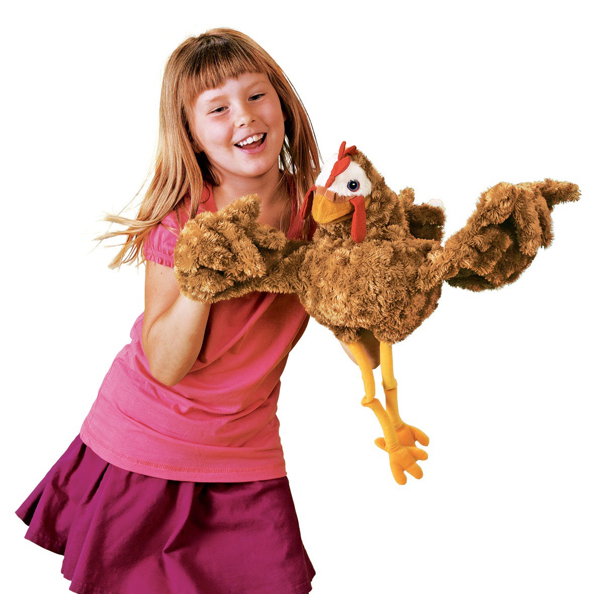 Lächelndes Mädchen spielt mit der Folkmanis Handpuppe Huhn in braunem Plüsch, rotem Kamm und gelben Beinen, Ganzkörperansicht.