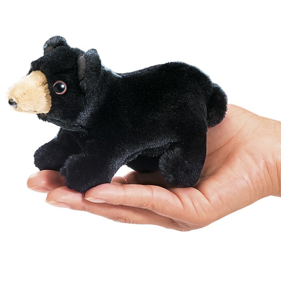 Folkmanis mini black bear finger puppet in black plush with beige muzzle, lying on a palm