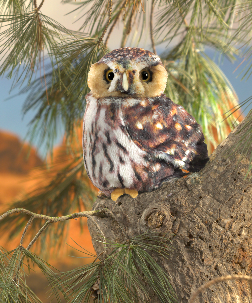 Folkmanis saw-whet owl hand puppet with brown spotted plumage sitting on a pine branch, front view