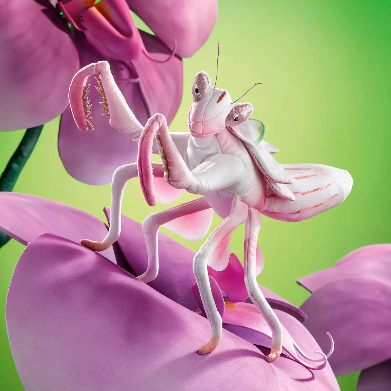 Folkmanis hand puppet orchid mantis in white and pink with raised forelegs, sitting on a large pink orchid bloom