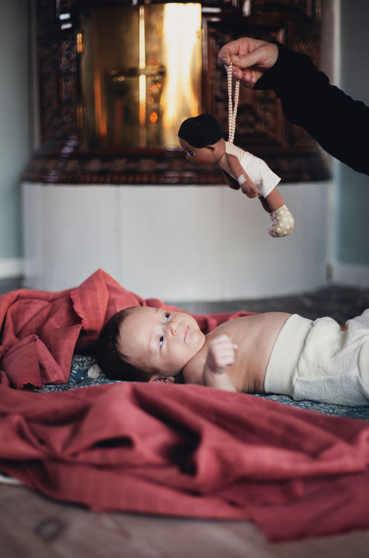 The Rubens EcoBuds mini doll Basil being handed to a lying baby