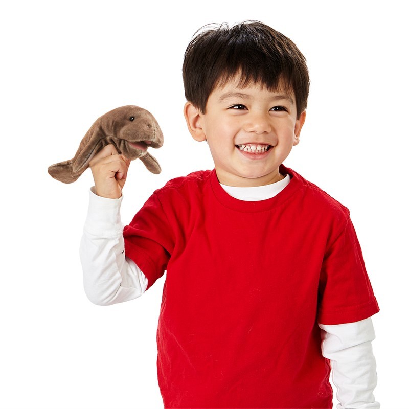 Smiling boy holding a Folkmanis mini manatee finger puppet in brown on his raised index finger