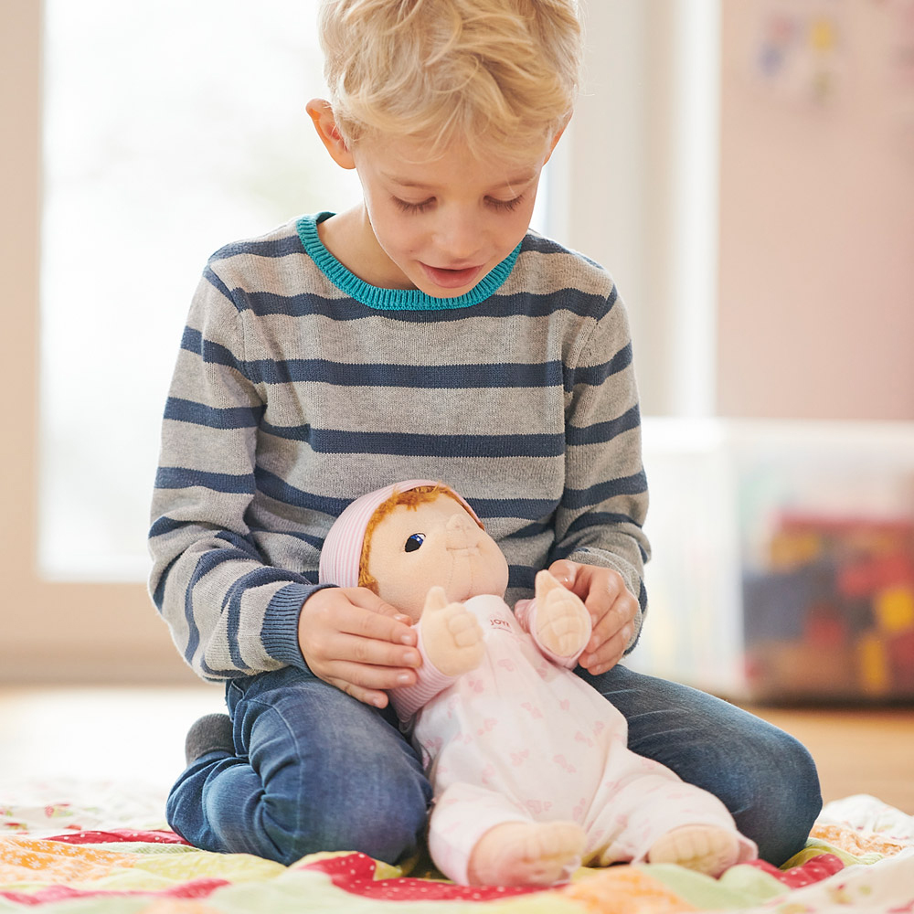 Child gently holding the Joyk empathy doll Baby Emma on their lap