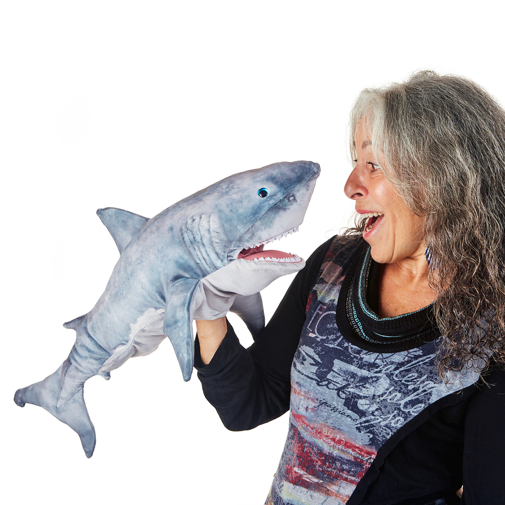 Folkmanis great white shark hand puppet in grey with open mouth, held by a woman on her hand