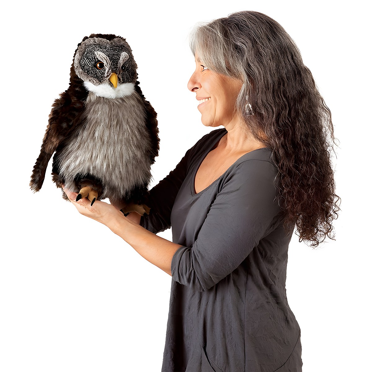 Woman holding a Folkmanis owl hand puppet with brown plumage, grey belly and yellow beak on her flat hand, side view