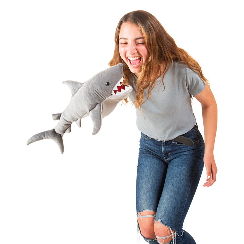 Laughing teenage girl being grabbed at the stomach by a grey Folkmanis shark hand puppet with red teeth