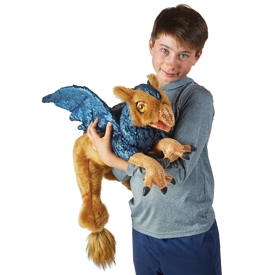 Boy holding a Folkmanis griffin hand puppet with blue wings, golden fur and reptile-like claws against a white background