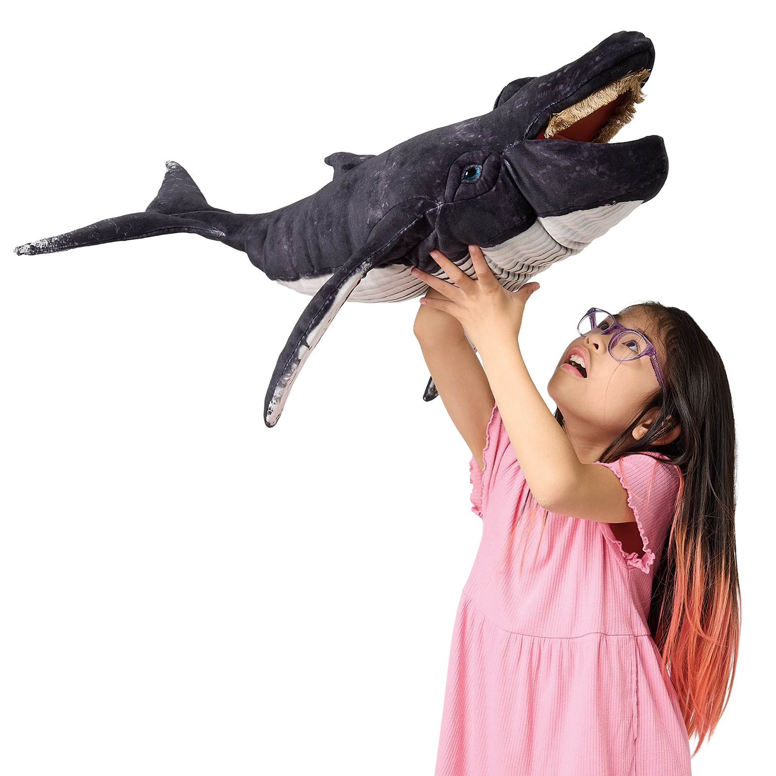 Girl holding up a Folkmanis humpback whale hand puppet with open mouth and baleen, dark grey plush with white belly
