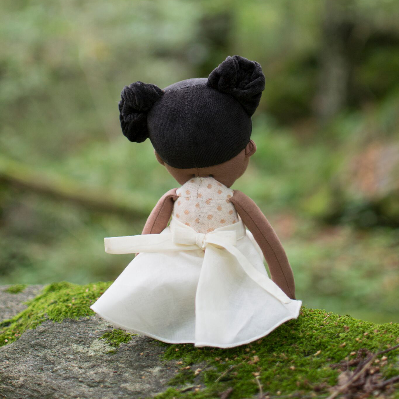 Rubens EcoBuds doll Poppy seen from the back with skirt bow on a rock