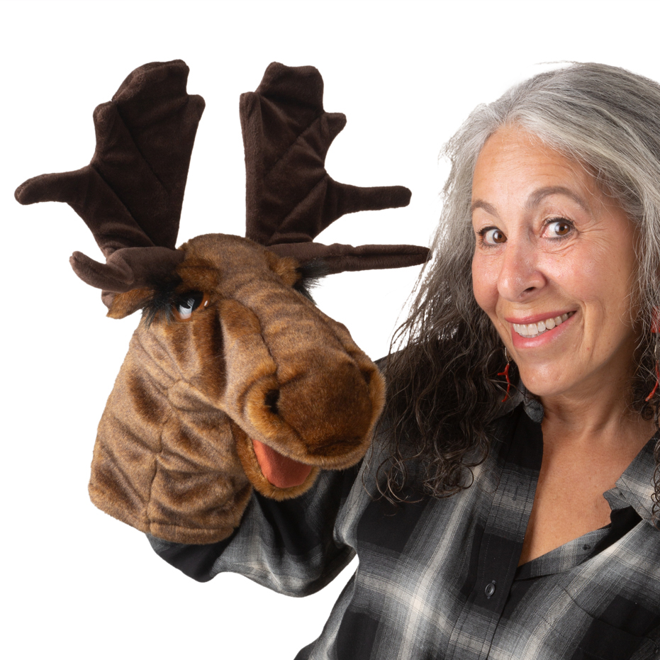 Folkmanis moose hand puppet with large antlers, brown plush fur and movable mouth, worn on the hand by a woman.