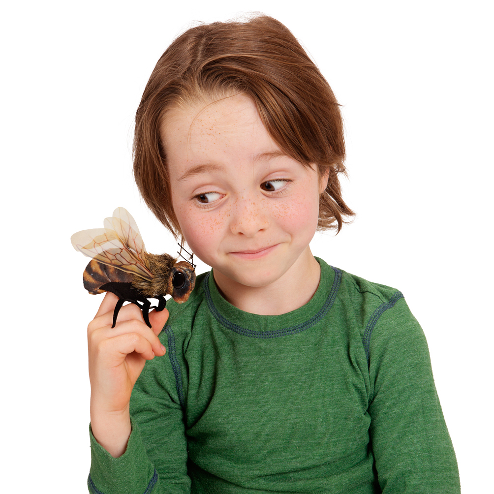 Child wearing green top balancing the Folkmanis Mini Bee finger puppet on a fingertip, close-up side view