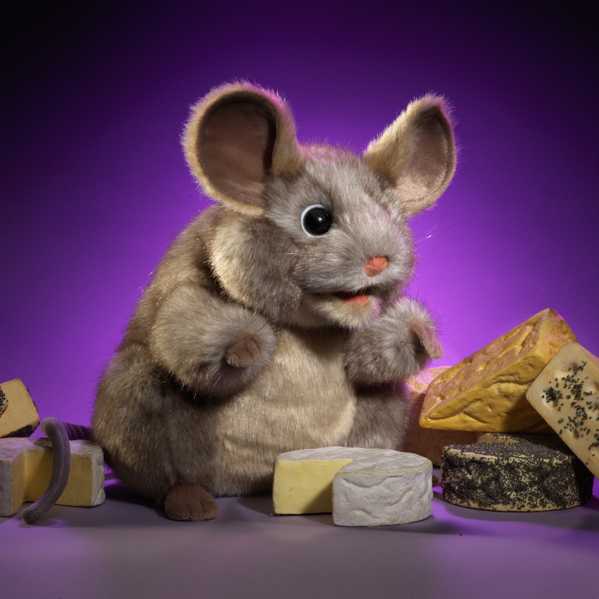 Folkmanis Handpuppe graue Maus mit großen Ohren, vor violettem Hintergrund, umgeben von verschiedenen Käsesorten