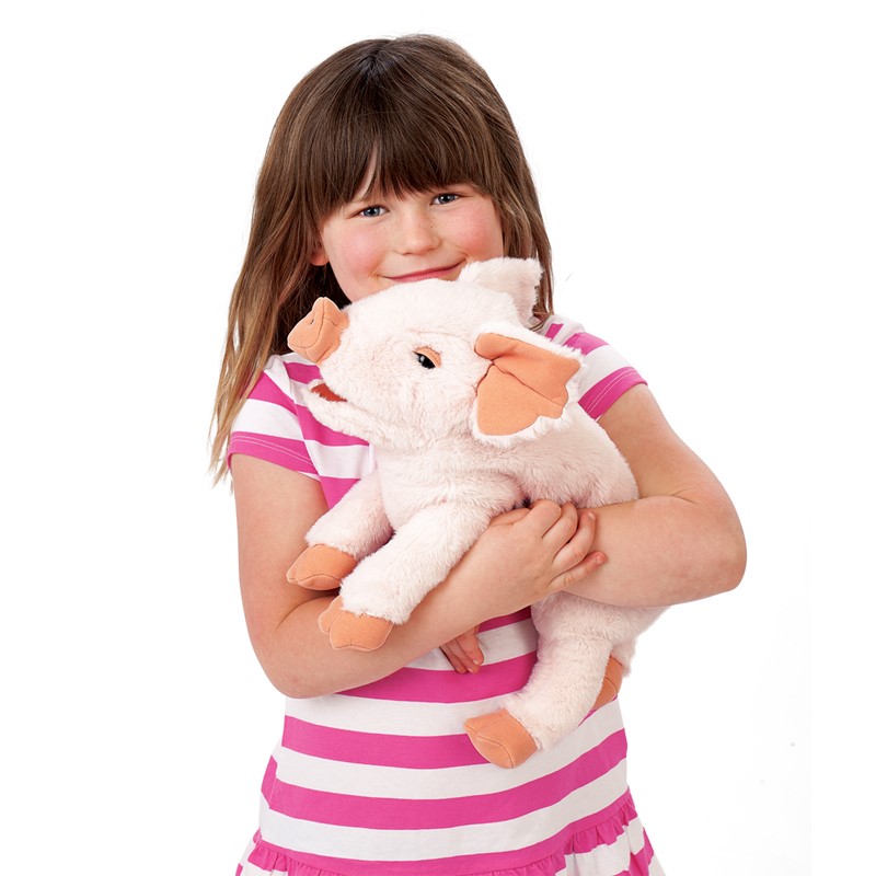 Girl holding the Folkmanis piglet hand puppet in pink with orange ears and hooves in her arms