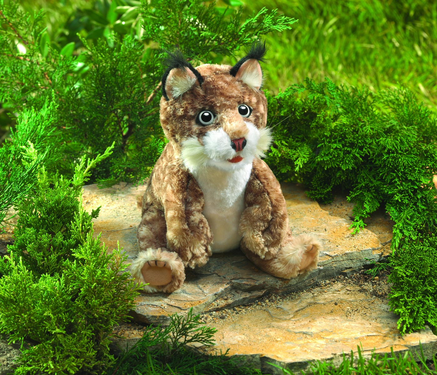 Folkmanis Handpuppe Rotluchs-Baby sitzend auf Stein, braun-geflecktes Fell, schwarze Ohrpinsel, weißer Bauch, geöffnetes Maul