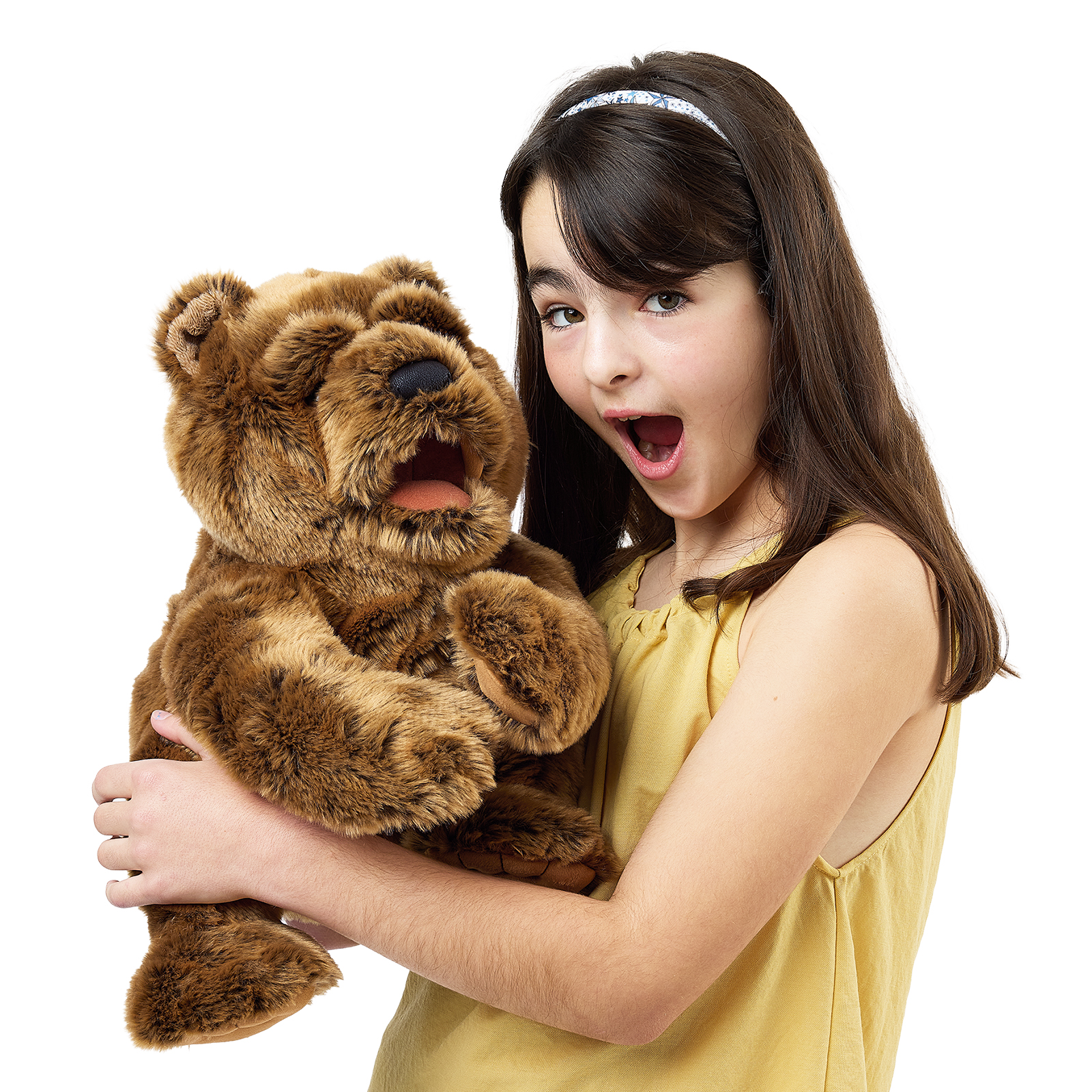 Folkmanis large bear hand puppet close to a girl's face, its head turned slightly with a closed mouth.
