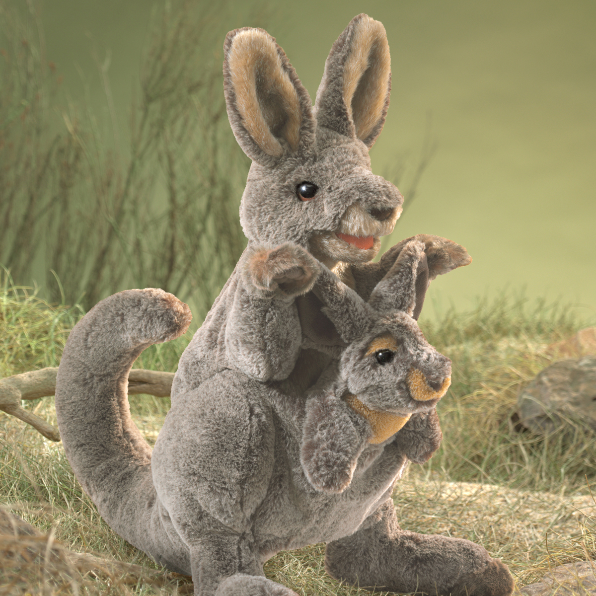 Folkmanis Handpuppe Känguru mit Baby in grauem Plüsch, Jungtier schaut aus dem Beutel, Frontalansicht vor Graslandschaft