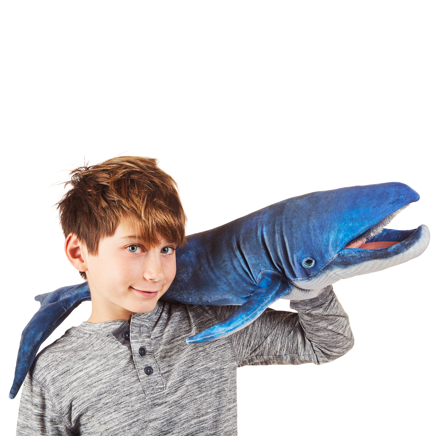 Boy operating a large Folkmanis blue whale hand puppet in dark blue with an open mouth over his shoulder