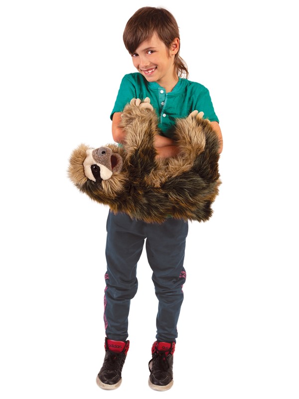 Laughing boy holding the Folkmanis three-toed sloth hand puppet with both arms, brown mottled fur, open mouth