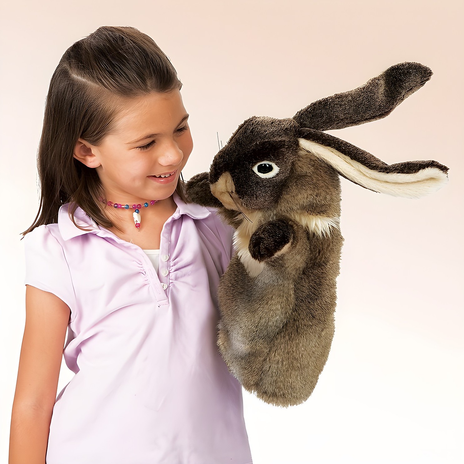Girl operating a large Folkmanis rabbit hand puppet with brown fur and long ears on her shoulder