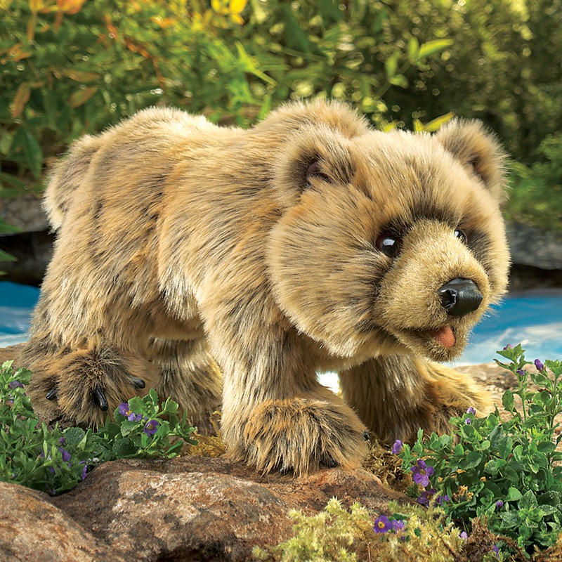 Folkmanis hand puppet grizzly bear with sandy brown fur in a crawling pose on rocks, side view