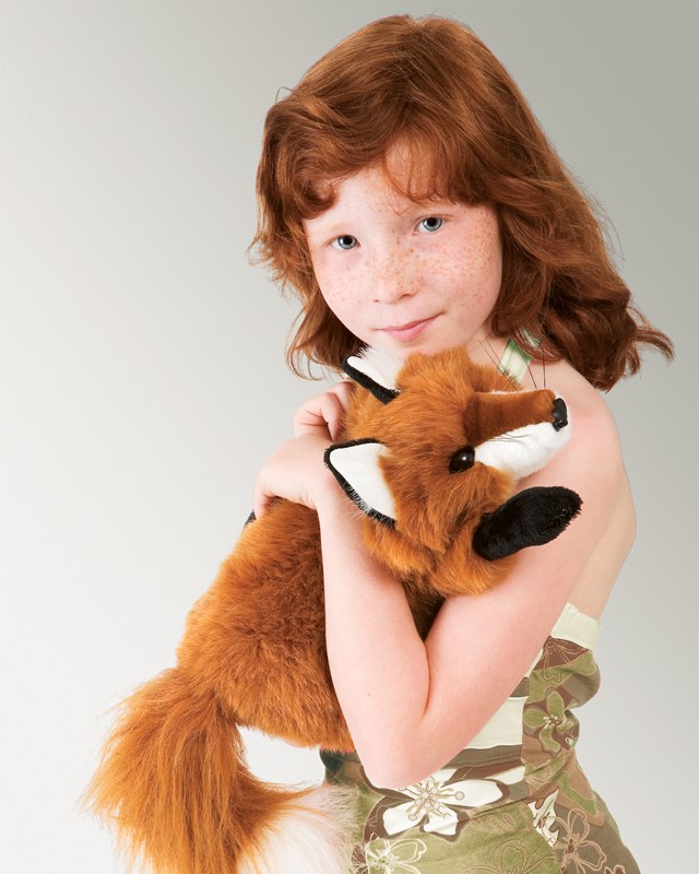 Girl holding the Folkmanis small red fox hand puppet with reddish-brown fur, white chest and black paws in her arms