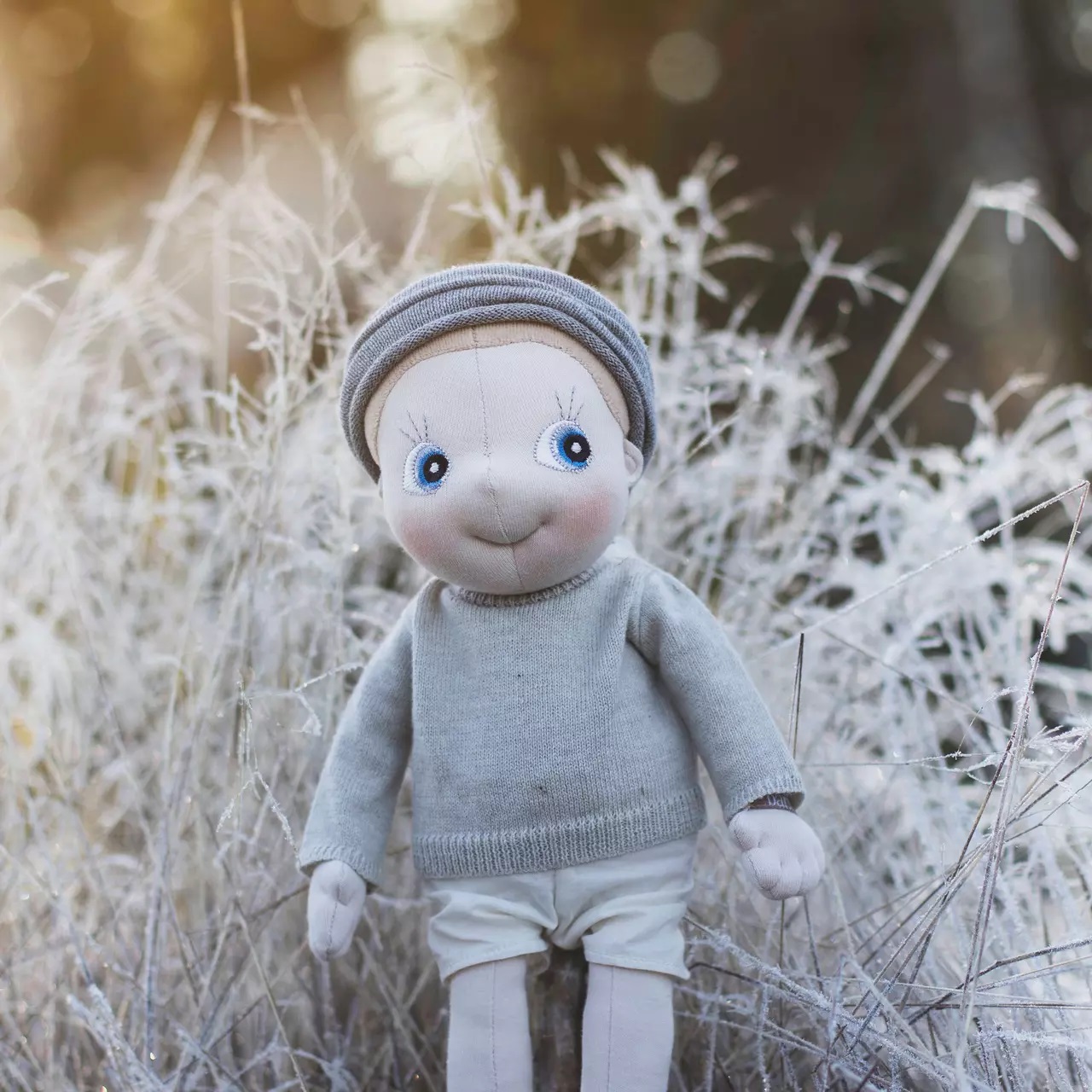 Rubens EcoBuds Puppe im Winter-Outfit mit Strickmütze im vereisten Wintergras