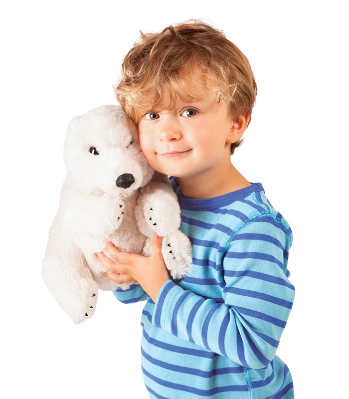 Young boy holding a white Folkmanis polar bear hand puppet against his cheek and smiling at the camera