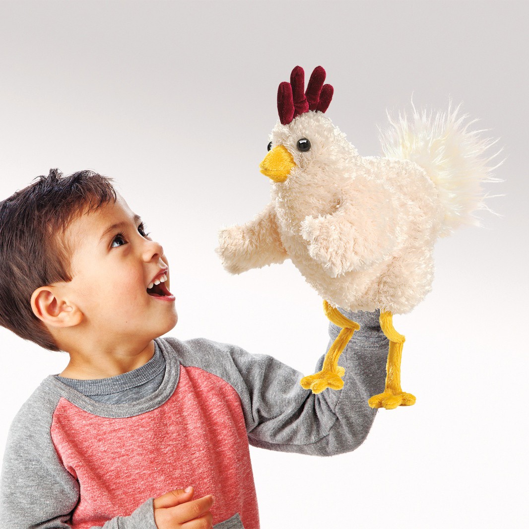 Boy playing with the Folkmanis Funky Chicken hand puppet featuring white plush, a dark red comb and yellow legs on his hand