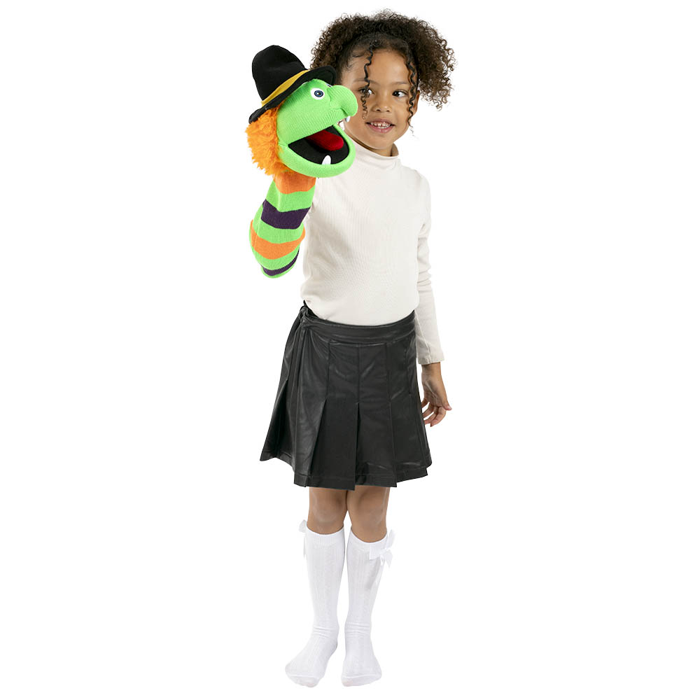 Kind spielt mit der Monster Sockenhandpuppe Hexe Wilma von der Puppet Company und führt die grüne Strickfigur mit schwarzem Hexenhut auf der Hand