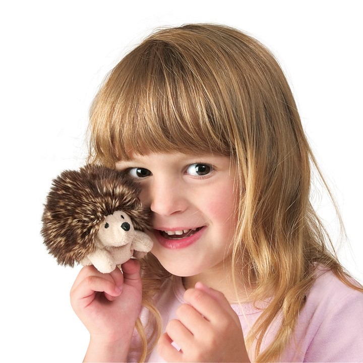 Girl holding a tiny Folkmanis mini hedgehog finger puppet with a brown spiny back and light belly close to her face