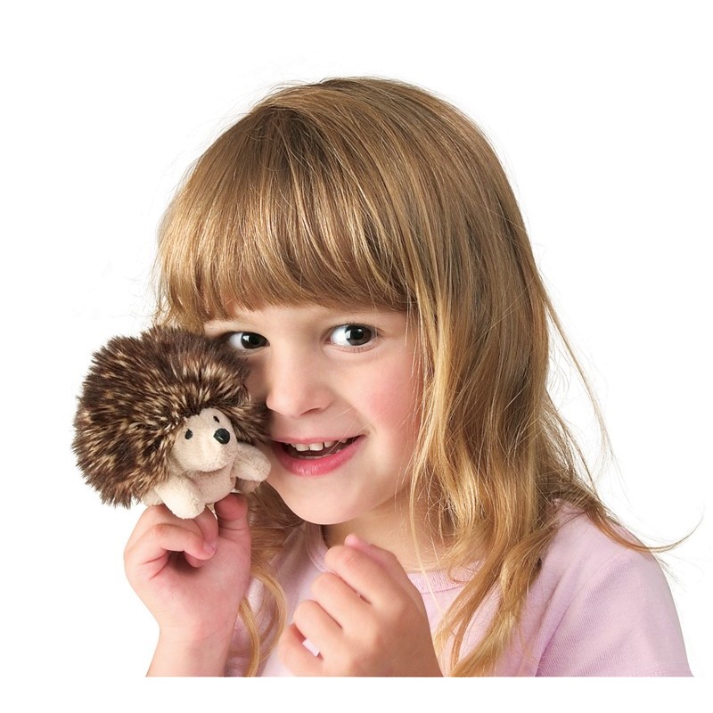 Girl holding a tiny Folkmanis mini hedgehog finger puppet with a brown spiny back and light belly close to her face