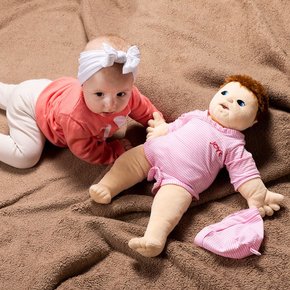 Baby next to the same-sized Joyk empathy doll Baby Lilly on a cuddly blanket