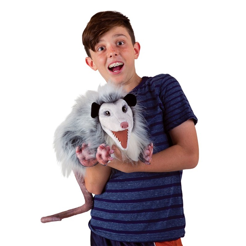 Junge hält Folkmanis Opossum-Handpuppe mit geöffnetem Maul und grau-weißem Zottelfell in den Armen.