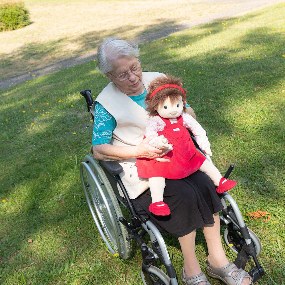 Senior lady in a wheelchair with the Joyk empathy doll Ingrid on her lap