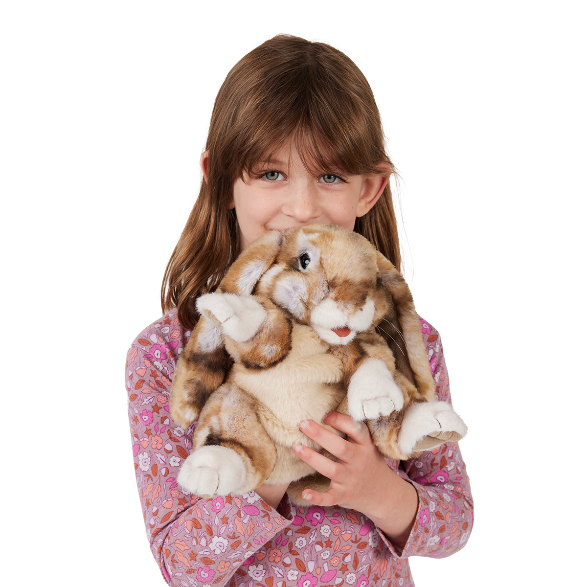 Mädchen hält Folkmanis Handpuppe Widderkaninchen mit braun-beigem Fleckenmuster und weißen Pfoten nah ans Gesicht