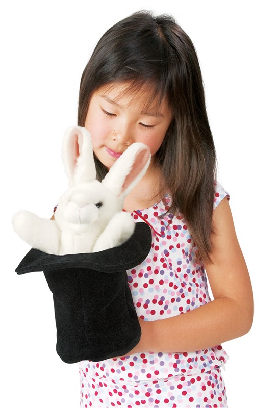 Mädchen hält Folkmanis Handpuppe weißes Kaninchen im schwarzen Zylinder und schaut lächelnd darauf herab.