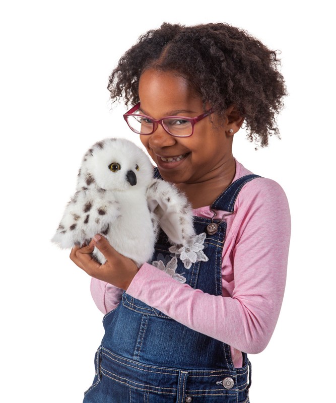 Girl holding the Folkmanis little snowy owl hand puppet with white plumage and dark spots in her hands