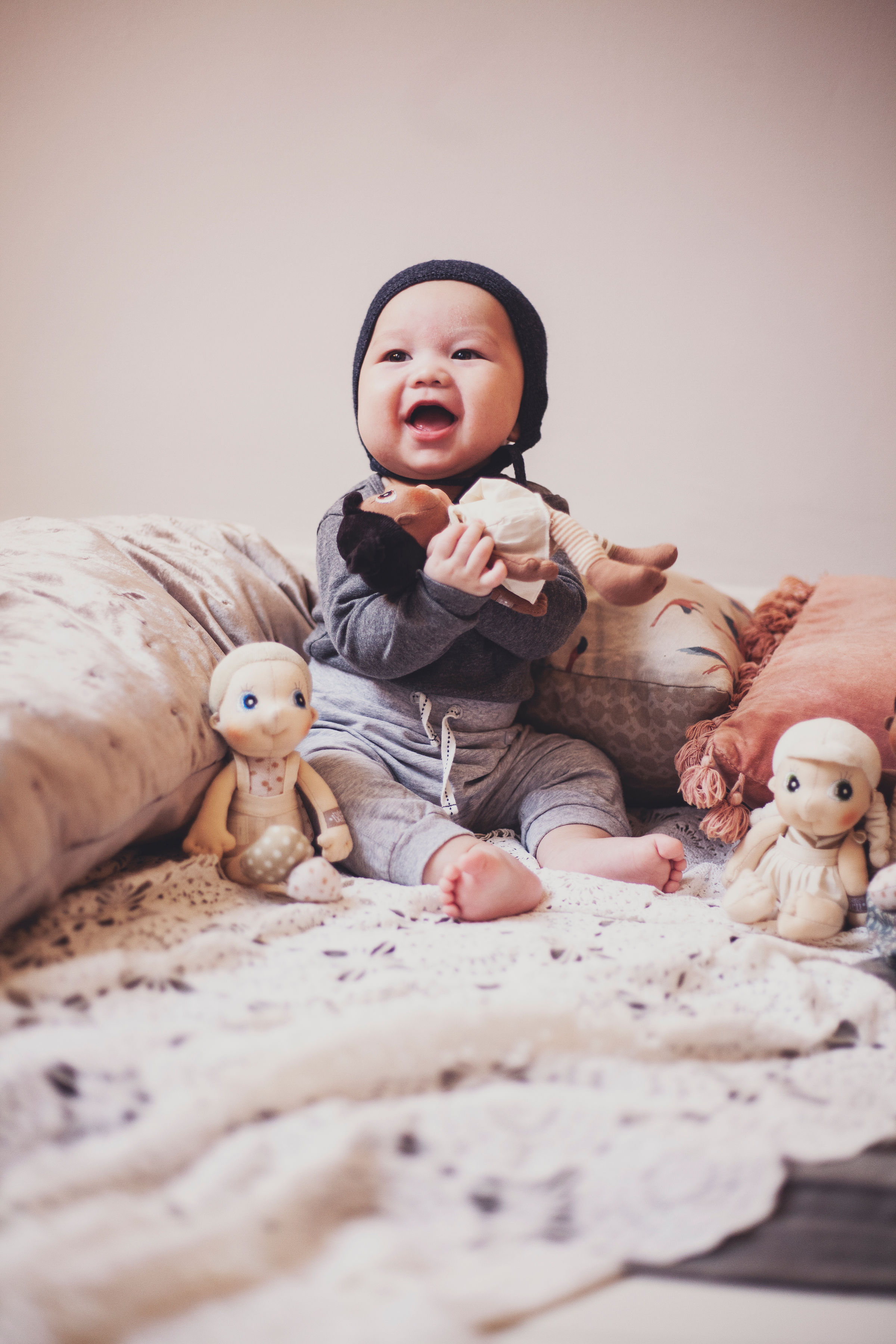 Laughing baby with the Rubens EcoBuds mini dolls on the bed