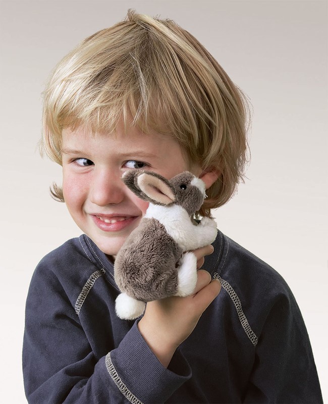 Lächelnder Junge hält eine kleine Folkmanis Fingerpuppe mini Kaninchen in Braun-Weiß auf dem Finger.