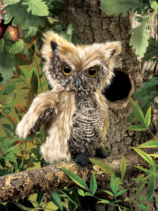 Folkmanis screech owl hand puppet with beige-brown plumage and yellow eyes, sitting on a branch in front of a tree hollow