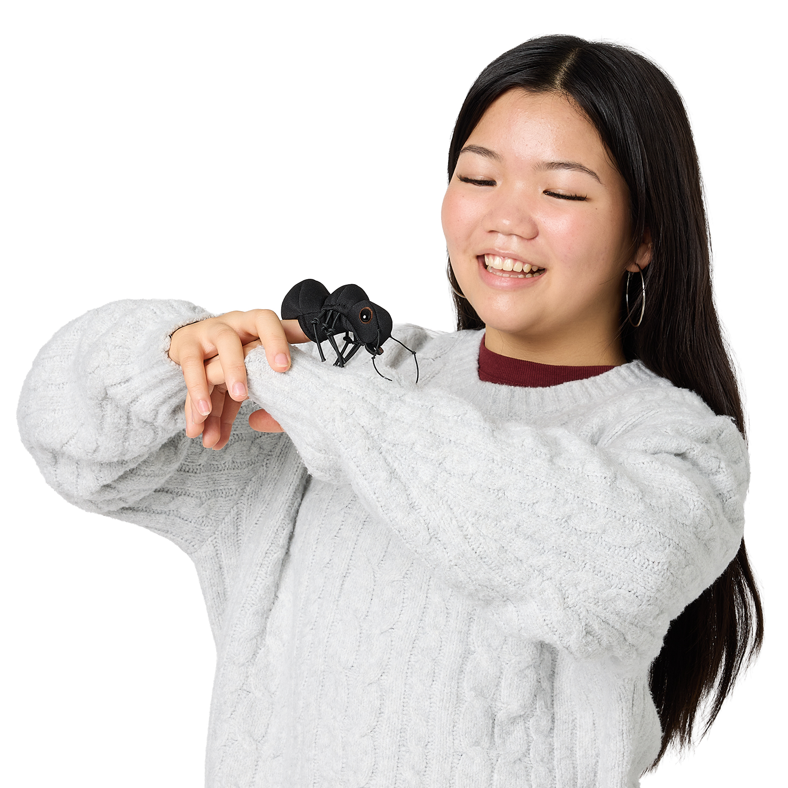 Folkmanis Fingerpuppe mini Ameise in Schwarz auf dem Zeigefinger einer lächelnden jungen Frau im Strickpullover