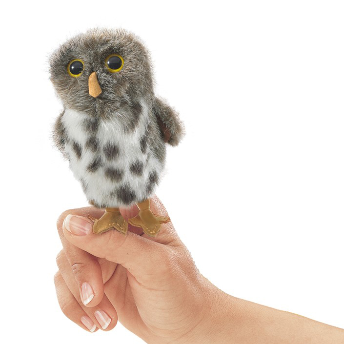 Folkmanis mini spotted owl finger puppet on an index finger, grey-white plumage with dark spots and yellow eyes