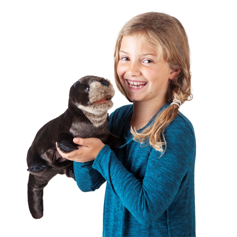 Smiling girl holding the Folkmanis river otter hand puppet with dark brown fur and a light-coloured belly in both hands