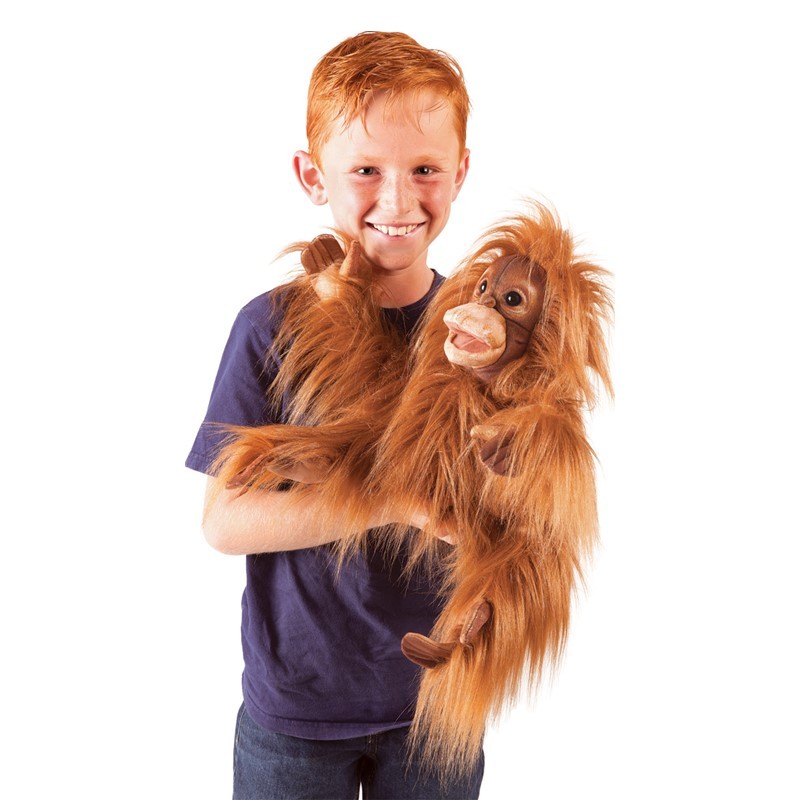 Junge hält Folkmanis Handpuppe Baby Orang-Utan mit rotbraunem Zottelfell und beweglichem Mund vor weißem Hintergrund